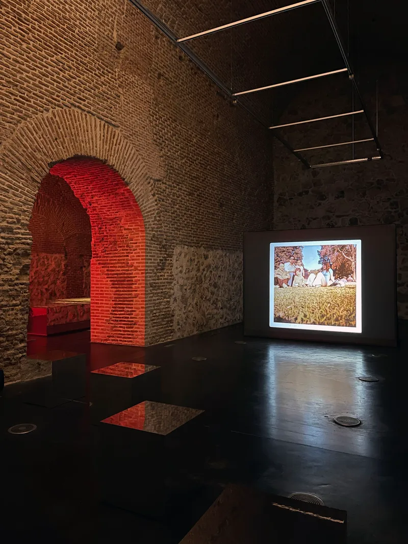 Gallery space with brick arches and a projected image illuminating the dark polished floor