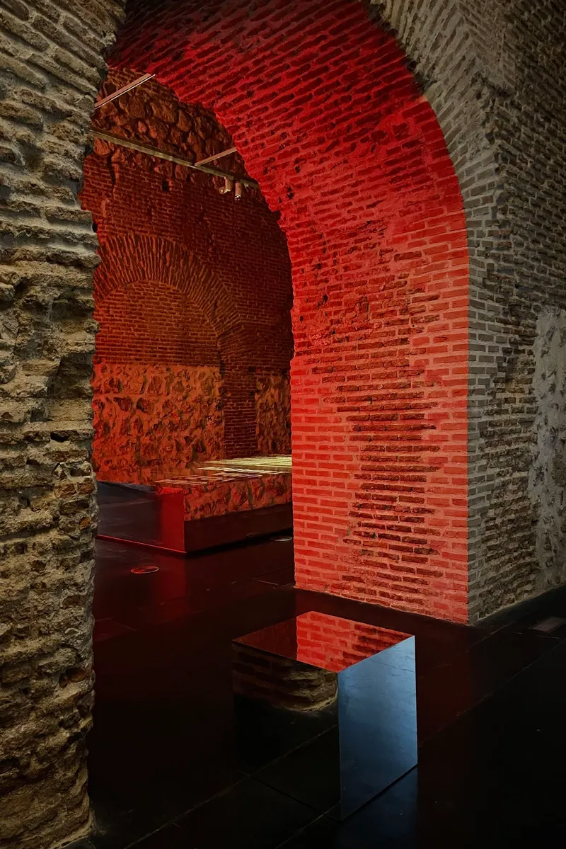 Close-up of a brick arch transitioning from red light to shadow above a reflective floor