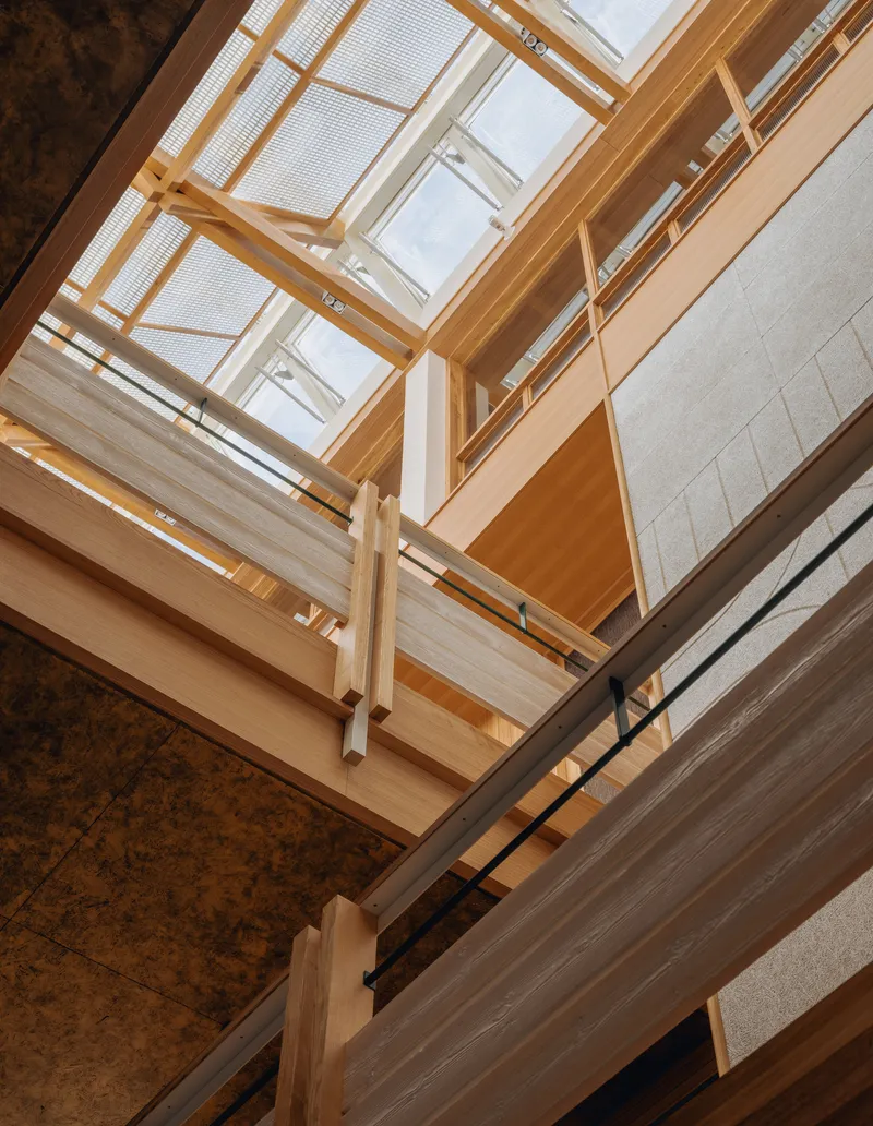 Looking up through the timber-framed stairwell with skylights and exposed rammed earth walls