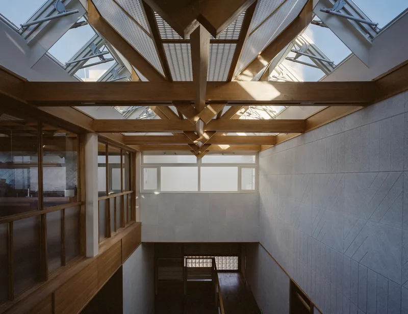 Interior view of timber roof trusses with skylights above a stairwell and tiled wall panels