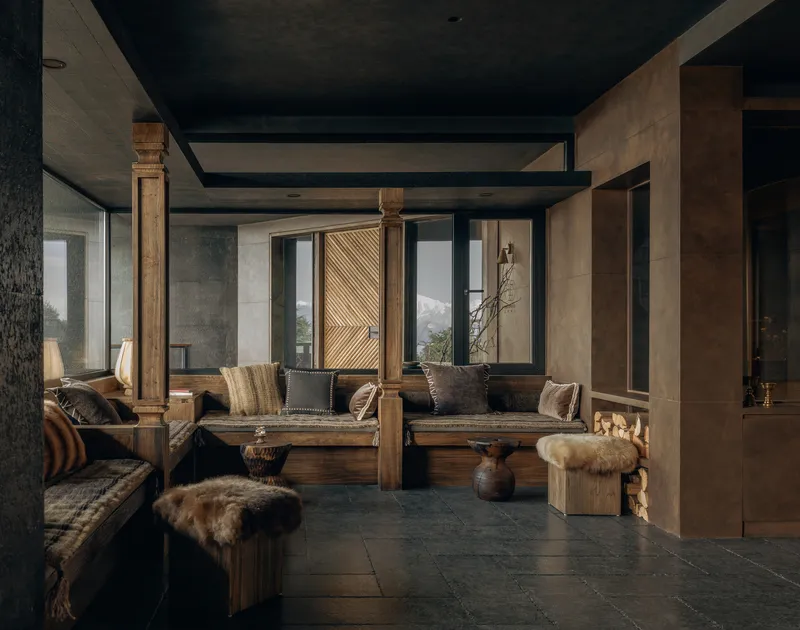 Lounge space with carved wooden columns, dark ceiling beams, and mountain views through tall windows