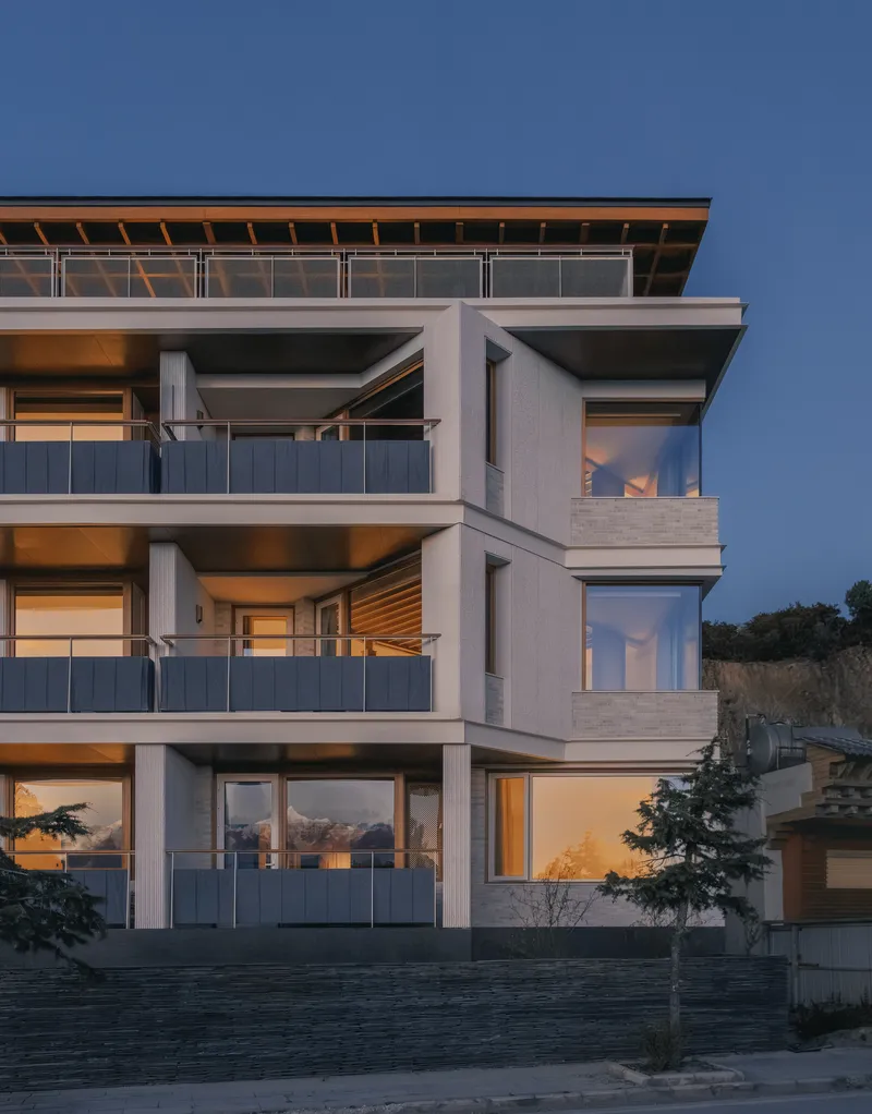 Three-story facade detail showing deep balconies and corner glazing at twilight