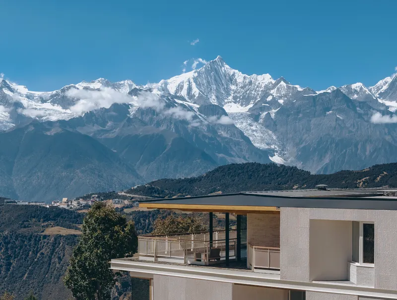 Rooftop terrace with timber canopy and glass railings against a backdrop of snow-capped mountain peaks