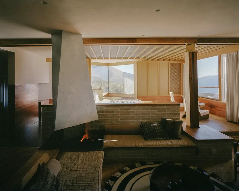 Sunken living area with concrete fireplace and timber-slatted ceiling framing mountain views