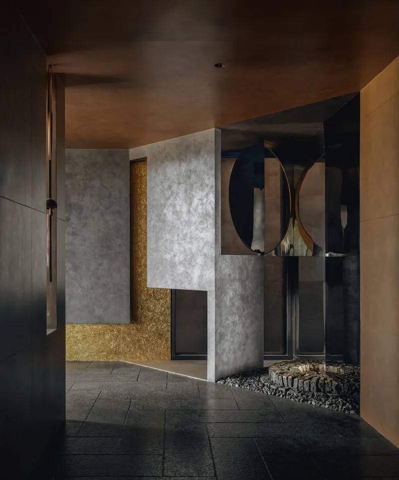 Entry foyer with gold-leaf wall panel behind concrete partition under timber ceiling