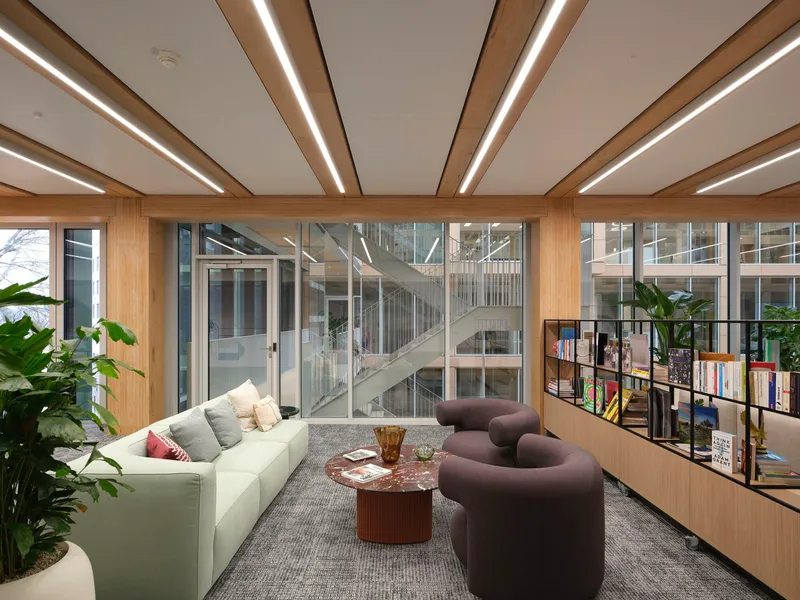 Seating area with timber-framed glazing overlooking a central staircase within the atrium