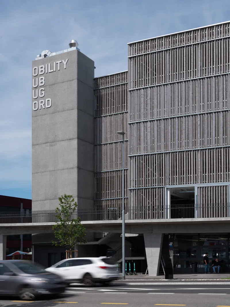 Street view of the ribbed concrete facade with vertical timber screen and passing traffic