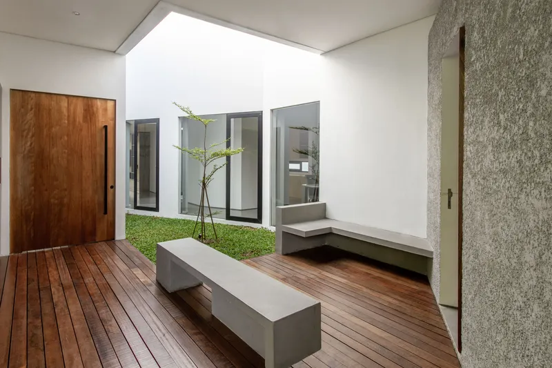 Interior courtyard with timber decking, grass lawn, concrete bench and clerestory window above