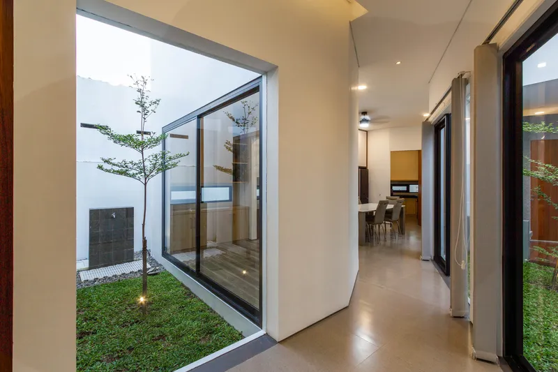 Hallway with pivoting glass wall opening to planted courtyard and polished concrete floor