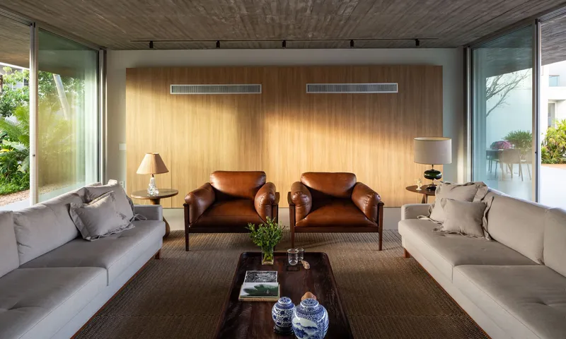 Sitting room with timber-paneled wall, glazed corners opening to garden, and afternoon sunlight filtering in