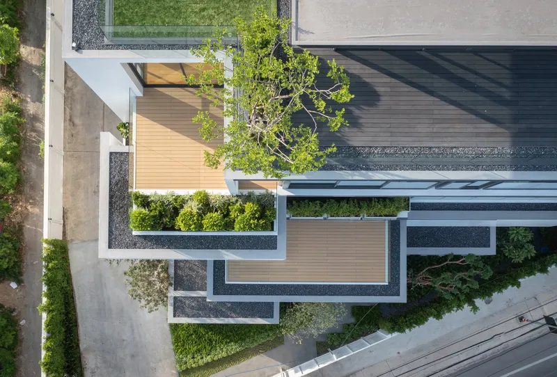 Aerial view of geometric courtyard with timber decking, planted beds, gravel borders and mature tree canopy
