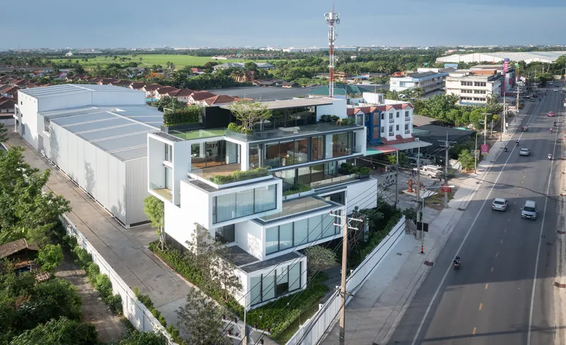 Aerial view of the terraced facade with offset volumes and rooftop gardens facing the roadway