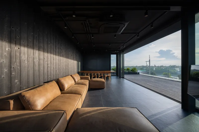 Interior lounge with leather seating and charred timber walls opening to a deck at dusk