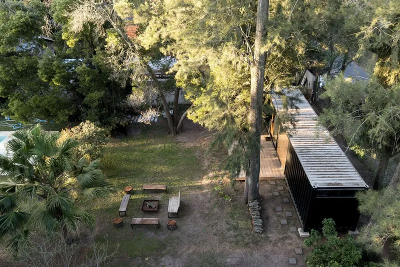 Aerial view of a corrugated metal pavilion and outdoor fire pit surrounded by mature trees