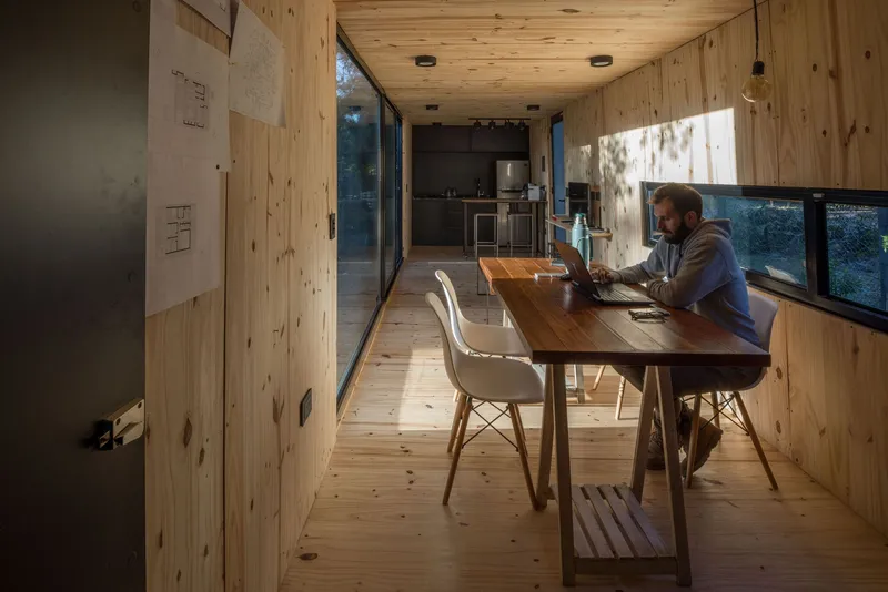 Person working at a timber table in the pine-lined interior with ribbon windows on both sides
