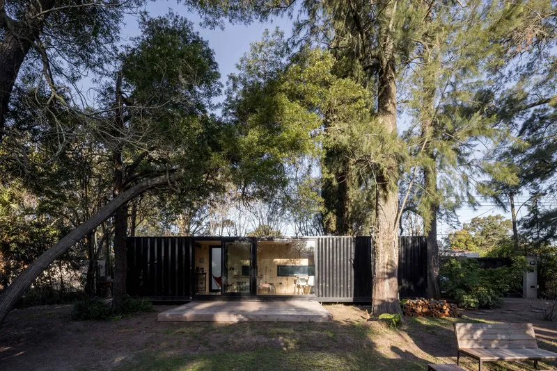 Front elevation showing corrugated metal panels flanking a central glazed section with timber cladding