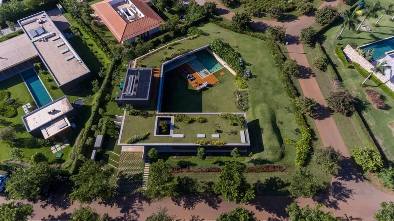 Aerial view of rectangular volumes arranged around courtyards and a swimming pool surrounded by lawn