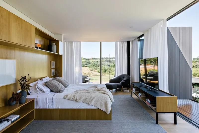 Bedroom with integrated timber joinery and floor-to-ceiling glazing overlooking the landscape