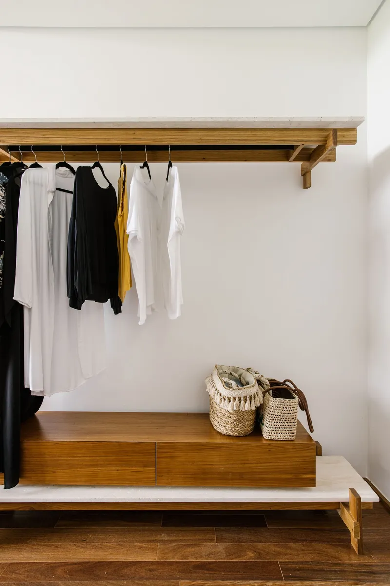 Wall-mounted timber shelf with hanging rail and low storage bench in the dressing area