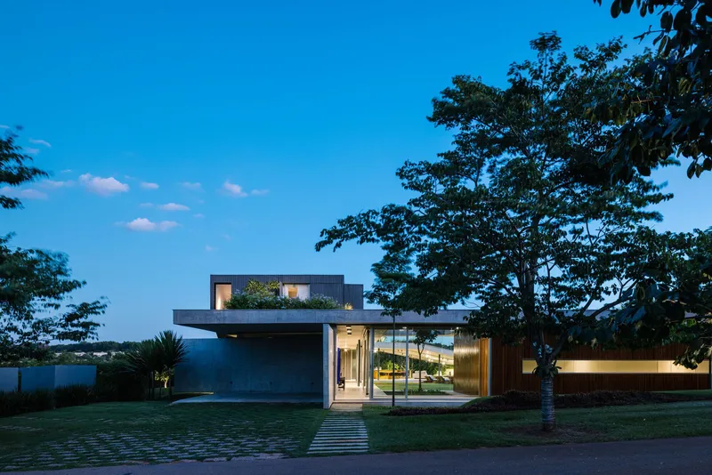 Street facade at dusk with illuminated interior visible through glazing and grid paver walkway