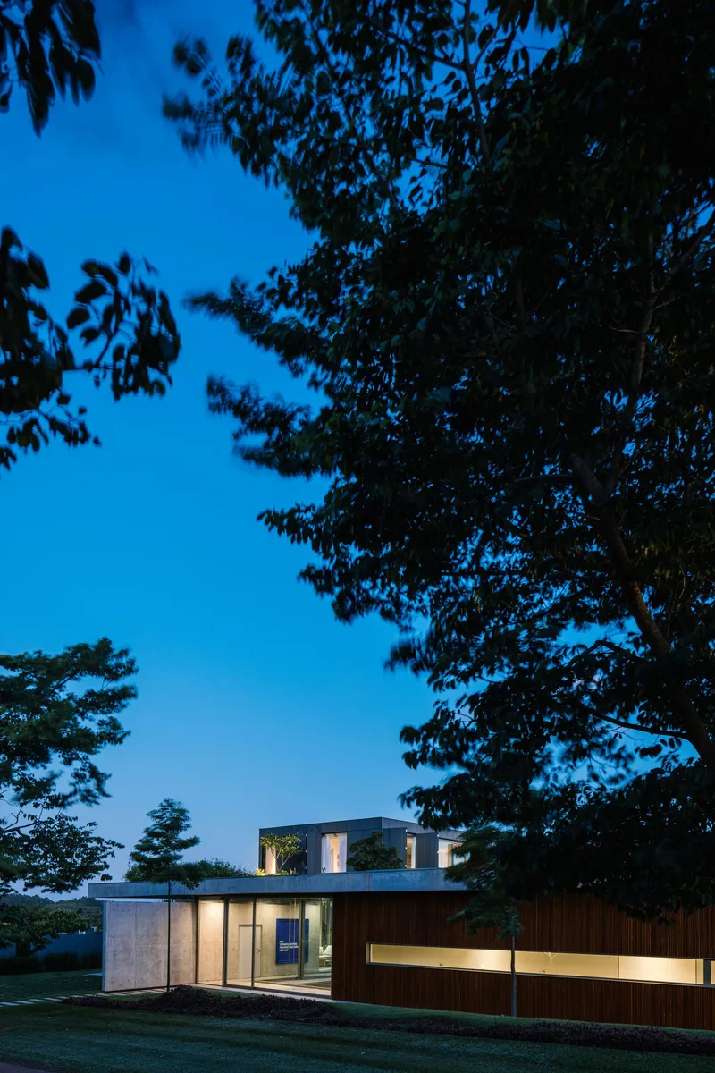 Garden elevation at twilight with timber cladding and second-floor volume framed by trees