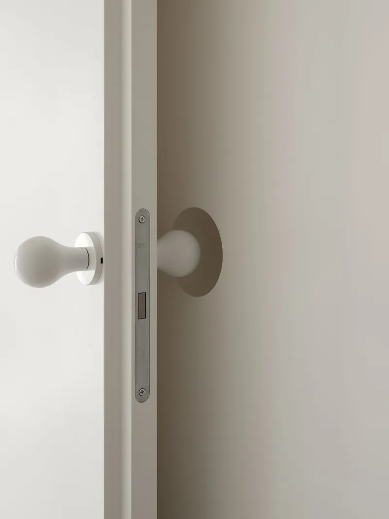 Detail of white spherical door handle with brushed metal backplate and mortise lock