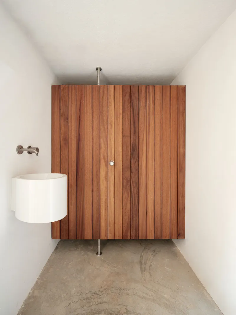 Vertical timber slat partition with cylindrical white basin and polished concrete floor