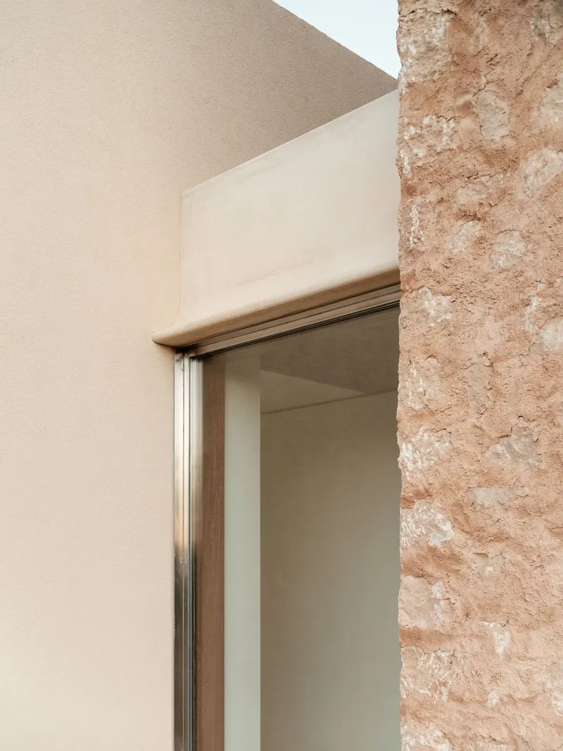 Detail of timber doorframe meeting the rough textured stone wall and smooth plaster corner