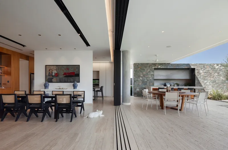 Open plan dining area with recessed ceiling track and floor-to-ceiling sliding glass door to outdoor terrace