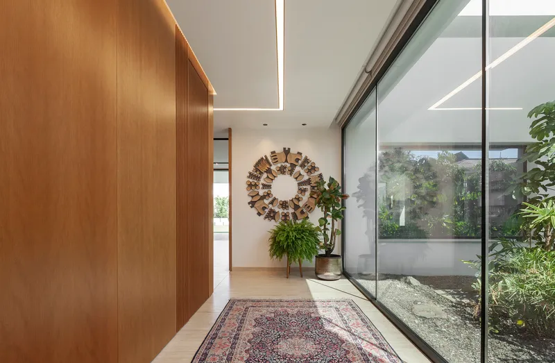 Entry hall with timber wall paneling and glass wall overlooking internal planted courtyard