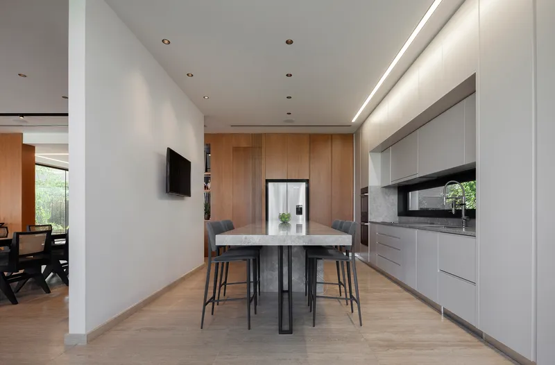 Kitchen with marble-topped island and timber cabinetry wall beneath a recessed cove ceiling light detail