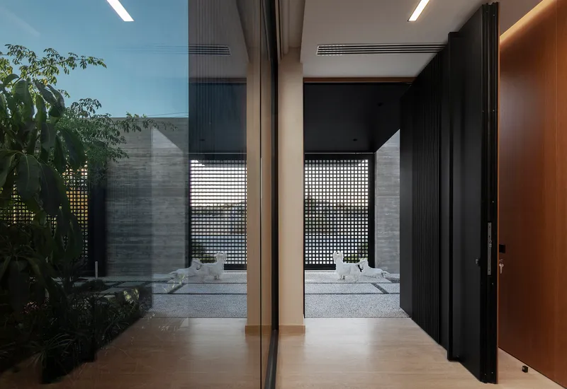 View through sliding glass doors to interior courtyard with perforated screen wall at dusk