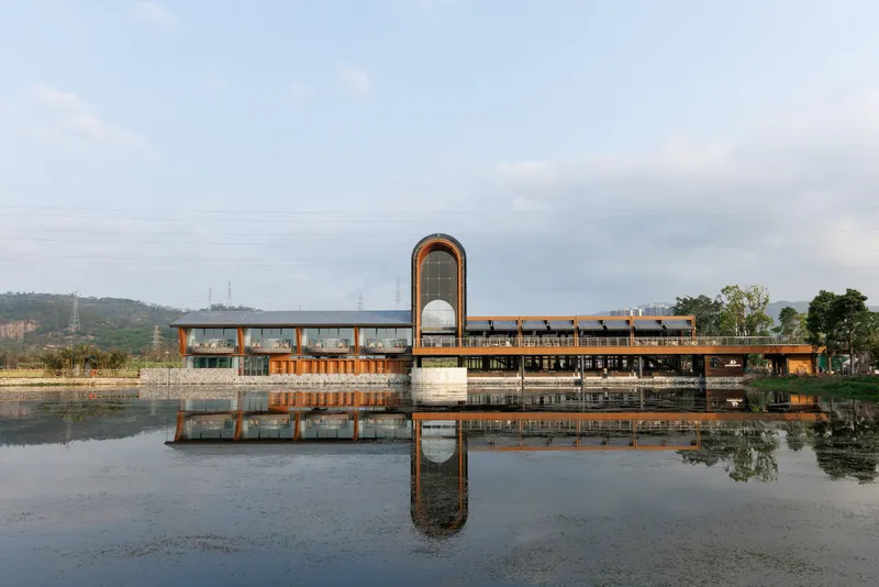 Waterfront facade with arched tower reflected in still pond under overcast sky