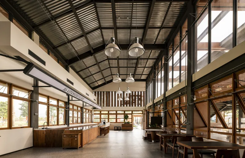 Open dining area with corrugated metal ceiling and timber screens filtering daylight