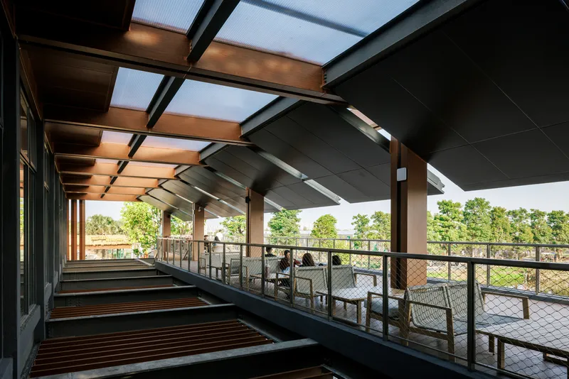Open-air terrace with metal railings and timber bench seating under deep roof overhangs and skylights