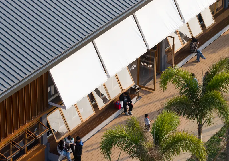Overhead view of courtyard deck with fabric canopies and visitors walking among potted palms