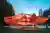 The image showcases a contemporary pavilion in an urban park setting. The structure features a strik