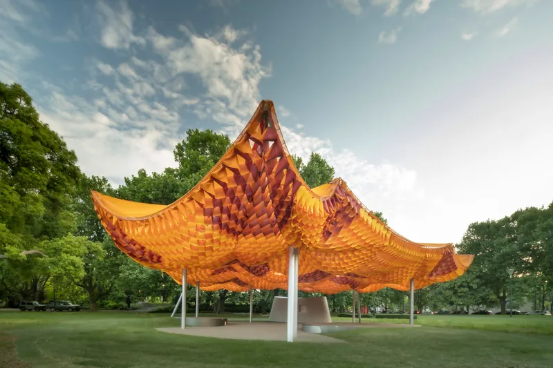 Central peak of the woven canopy rising above its curved edges with trees in background
