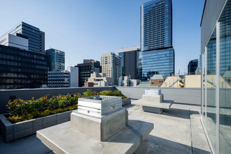 Rooftop terrace with concrete planters, raised garden beds, and stepped seating under clear blue sky