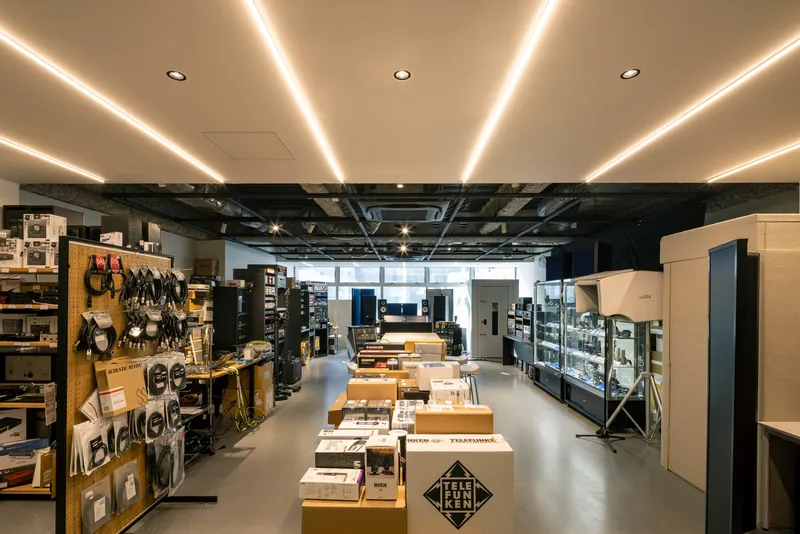 Retail interior with linear LED ceiling coves above exposed black ductwork and merchandise displays