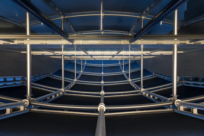 Upward view of circular steel structural rings with LED strips at dusk