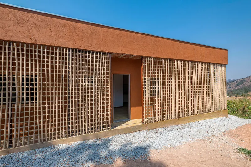 Entry view showing timber lattice panels flanking a doorway in an earthen facade