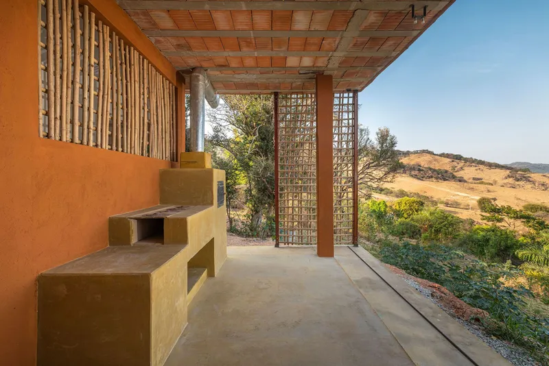 Covered terrace with terra cotta tile ceiling, lattice screens, and earthen bench facing hills