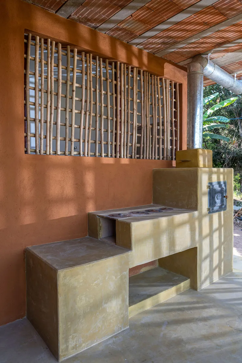 Covered porch with bamboo lattice screen above a terracotta wall and terraced yellow concrete seating