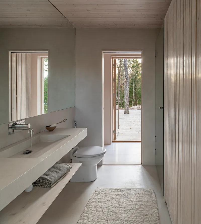 Bathroom with cast concrete vanity and open doorway leading to the surrounding forest