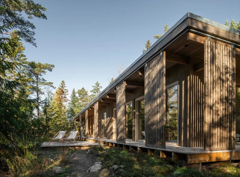 Long view of the timber-clad facade with exposed beam overhang and vertical slat screens
