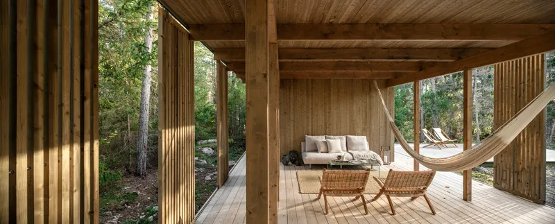 Covered porch with timber columns, plank ceiling and hammock opening to the forest