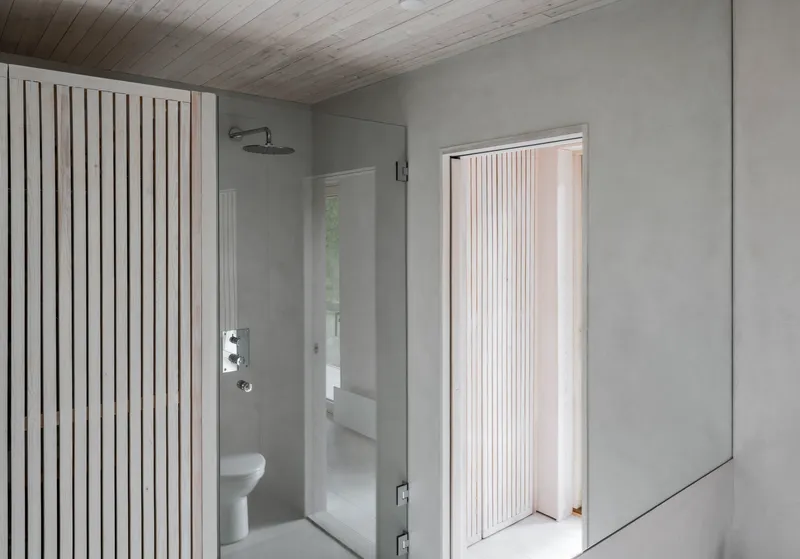 Bathroom with vertical timber slat screen, glass shower enclosure, and pale wood plank ceiling