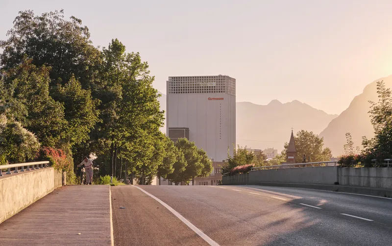 View along the highway toward the concrete tower with perforated crown at sunset with mountain backdrop