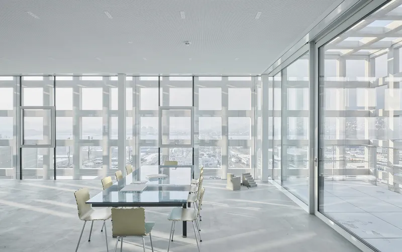 Glass-walled meeting room with sliding doors opening to a terrace framed by the perforated facade